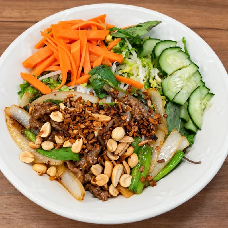 Stir-fried beef vermicelli bowl with peanuts, fried shallots, pickled carrot and cucumber