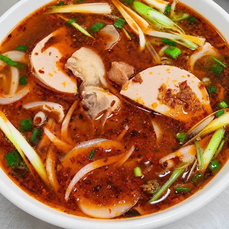 Bún bò Huế with a red chili-lemongrass broth, sliced beef, pork and round rice noodles